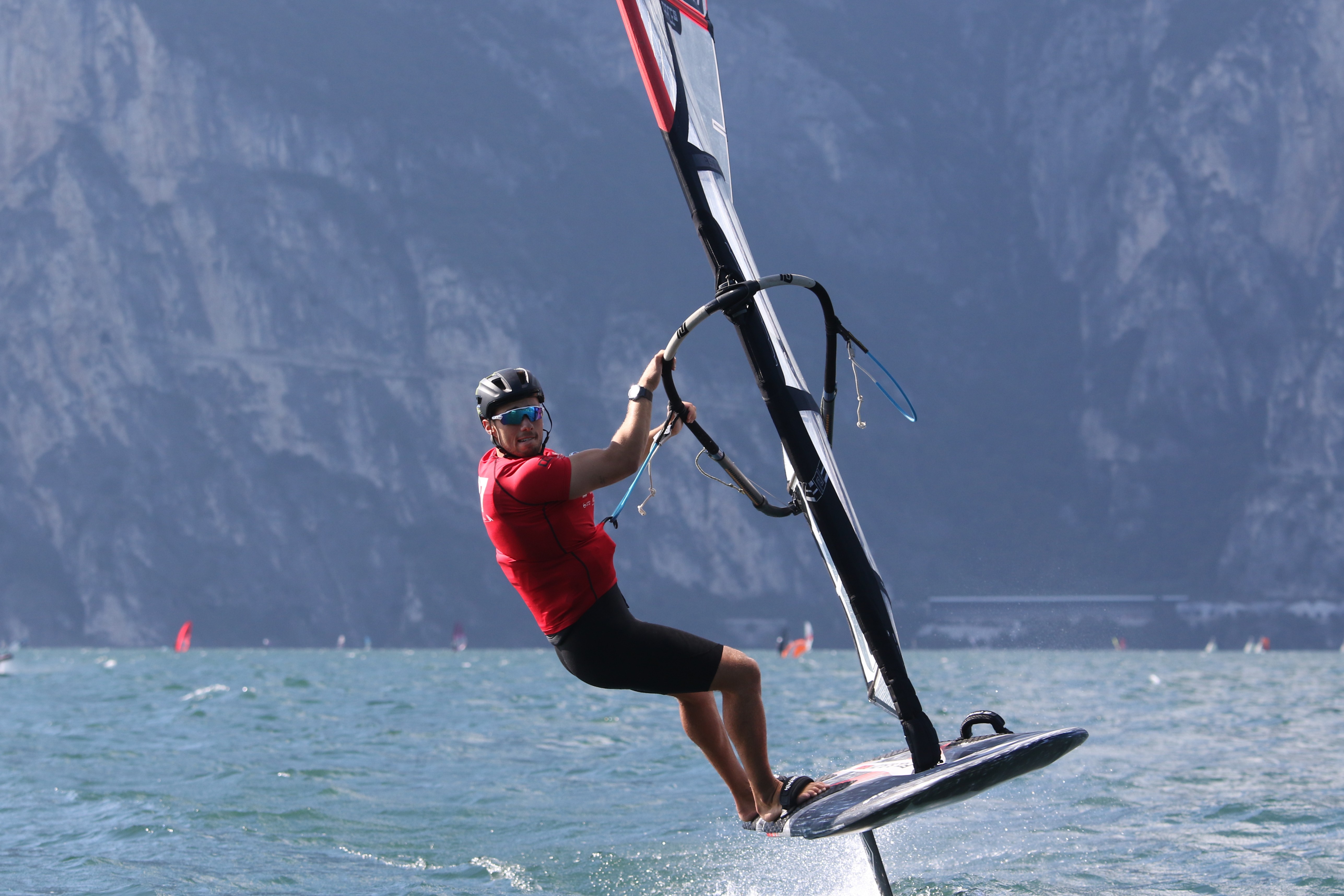 Foiler carving a turn on a lake with mountains behind