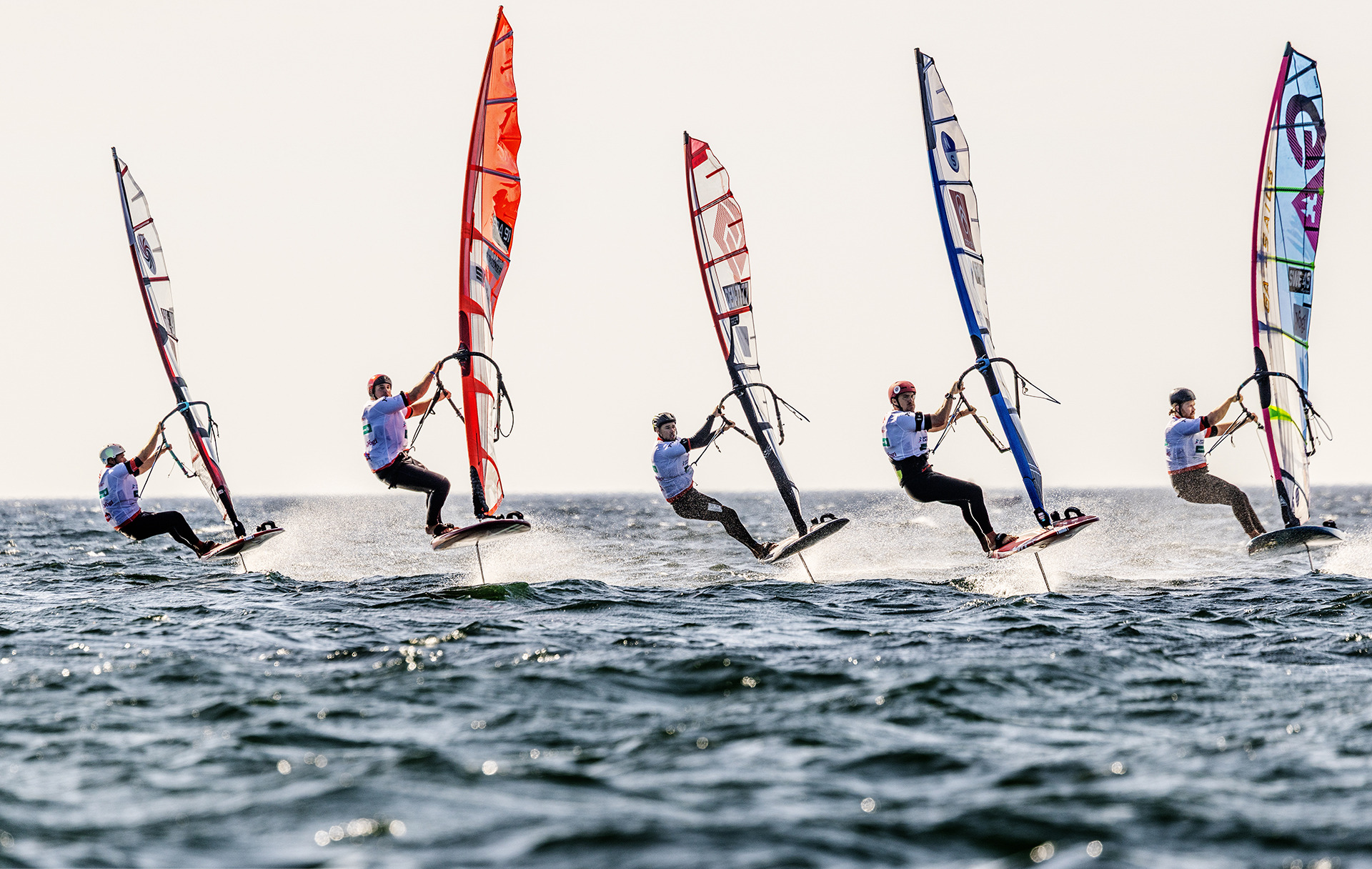 Five foil slalom riders flying side by side over the water on the PWA World Tour