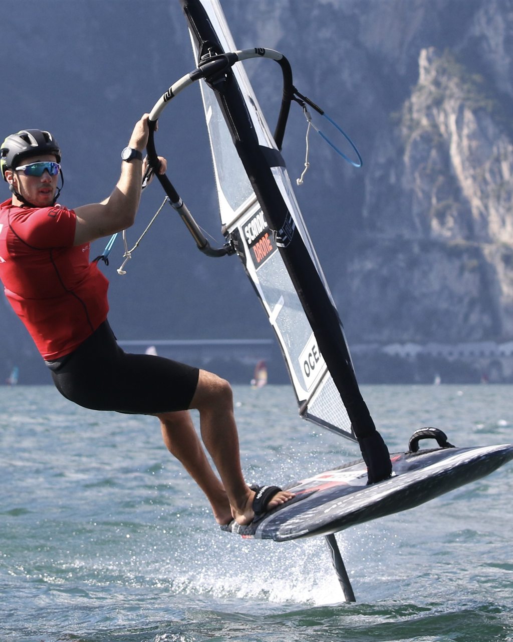 Noah foiling at speed on Lake Garda with the mountains behind him