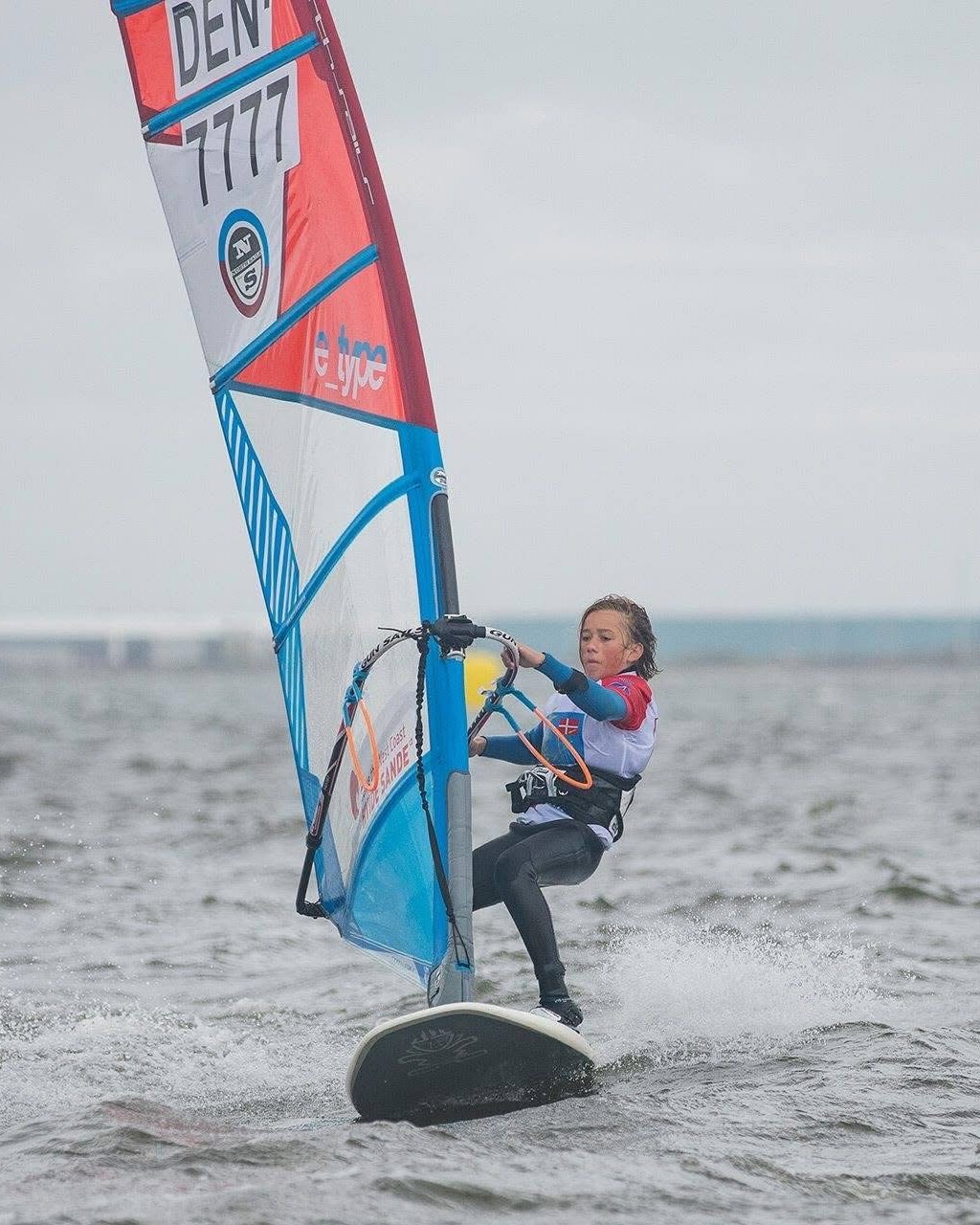 Young Noah racing a windsurfer with sail number DEN-7777